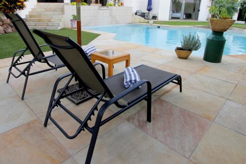 two lawn chairs sitting next to a pool at La Dolce Vita Umhlanga Guesthouse in Durban