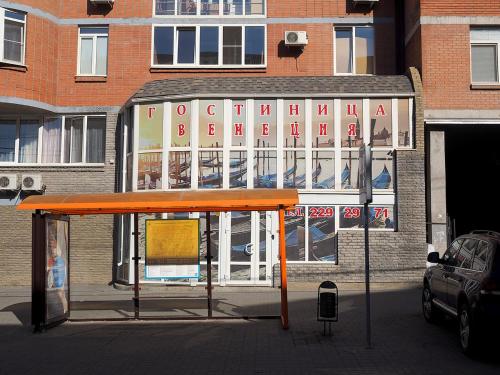 a bus stop with an orange roof in front of a building at Venecia Hotel in Rostov on Don