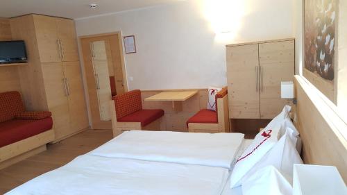 a room with a bed and two red chairs at Hotel Sole Family Hotel in Predazzo