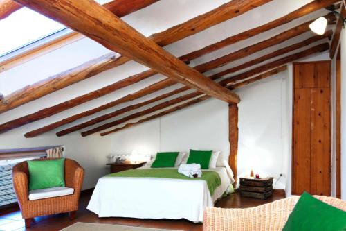 ein Schlafzimmer mit einem Bett und einem Stuhl sowie Holzdecken in der Unterkunft Casa La Sabina Rural in Calomarde