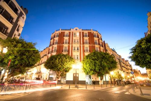 a tall building on a city street at night at Petit Palace Ruzafa in Valencia