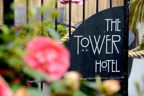 a sign that reads the tower hotel next to flowers at Tower Hotel in Lincoln