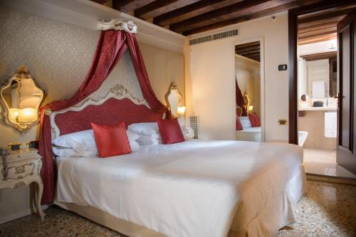 a bedroom with a large white bed with red pillows at Ruzzini Palace Hotel in Venice