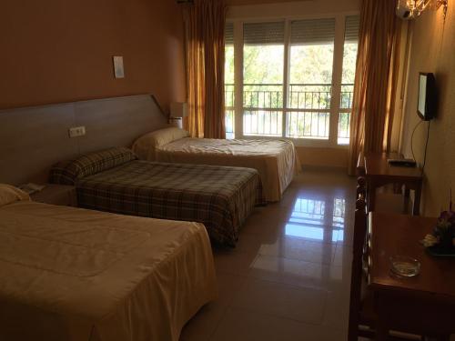 a hotel room with two beds and a window at Hotel Manzanares in Manzanares