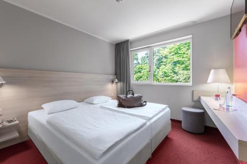 a hotel room with a white bed and a window at Serways Hotel Bruchsal West in Forst