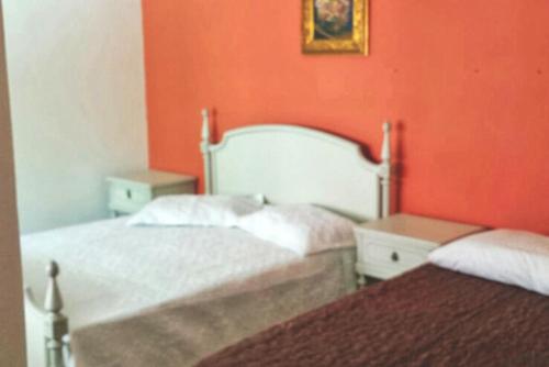 two beds in a room with orange walls at Pousada Musleh in Rio Grande