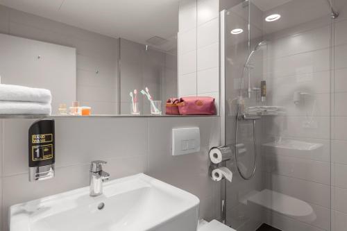 a white bathroom with a sink and a shower at Serways Hotel Weiskirchen Nord in Rodgau