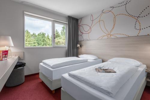 a hotel room with two beds and a window at Serways Hotel Weiskirchen Nord in Rodgau