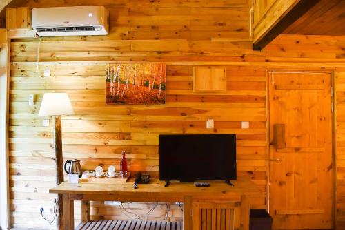a room with a wooden wall with a television on a table at Suro Treehouse Resort in Shogi