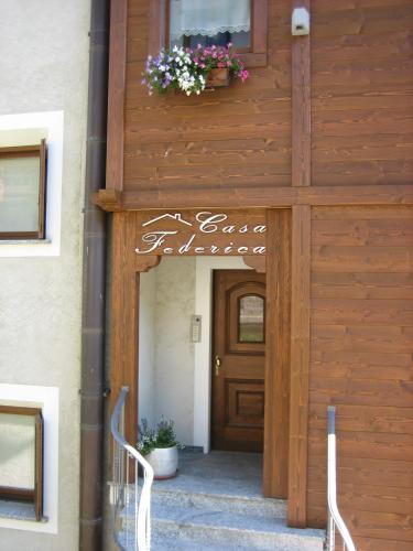 a wooden entrance to a house with a door and flowers at Residence Casa Federica in Valfurva