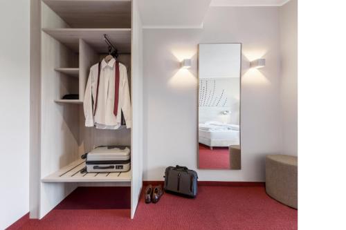 a walk in closet with a mirror and a bed at Serways Hotel Remscheid in Remscheid