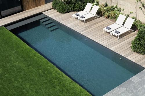 a swimming pool with two lounge chairs next to a yard at B&B For 2-Wellness For 2 in Bruges