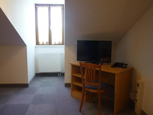 Habitación con escritorio, TV y silla. en Wirtshaus Zur Bina, en Vilsbiburg