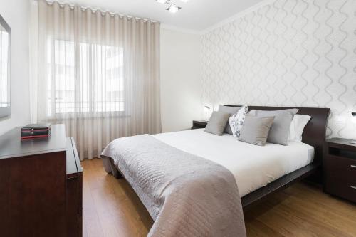 Un dormitorio blanco con una cama grande y una ventana. en Jasmineiro III by An Island Apart, en Funchal