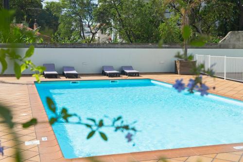 a swimming pool with lounge chairs next to a wall at Jasmineiro III by An Island Apart in Funchal