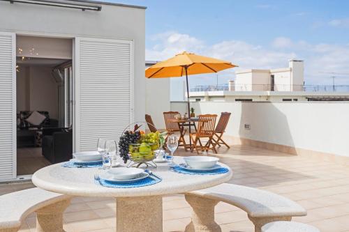 a table with a bowl of fruit and an umbrella on a patio at Jasmineiro III by An Island Apart in Funchal