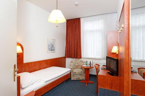 a hotel room with a bed and a chair at Hotel Stadt Hannover in Göttingen