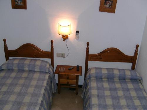 1 dormitorio con 2 camas y una lámpara en la pared en Hostal Alicante en Granada