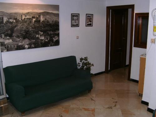 un sofá verde en una habitación con una foto en la pared en Hostal Alicante en Granada