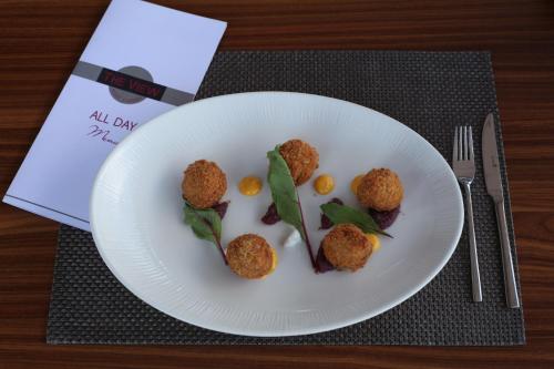 a white plate with meatballs and greens on a table at SAZ City Life Boutique Hotel in Ioannina
