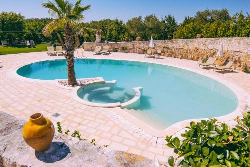 a large swimming pool with a palm tree next to it at Masseria Rosa Trulli Relais in Alberobello