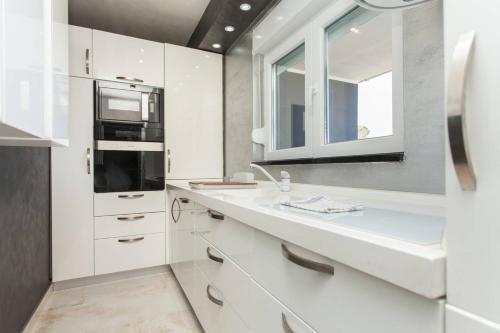 a white kitchen with a sink and a microwave at Teo Apartment in Pula