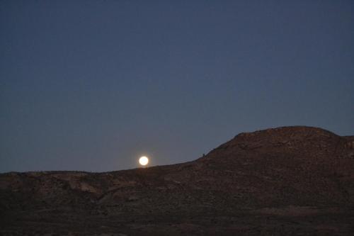 a moon sitting on top of a hill at night at Sperrgebiet Lodge in Springbok
