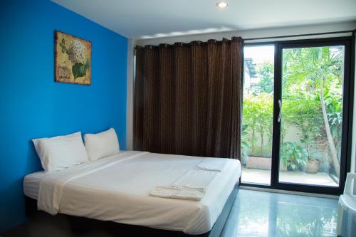 a blue room with a bed and a large window at Varinda Hostel in Bangkok