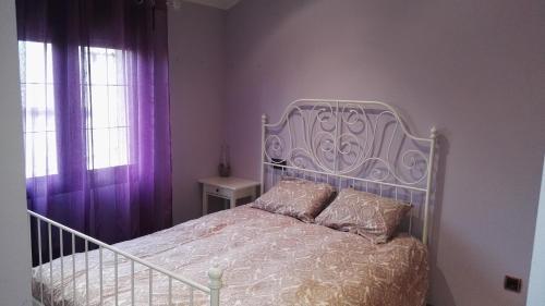 a bedroom with a white bed with purple curtains at Casa El balcón de Iria in Otero de Herreros