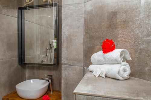 a bathroom with a sink and a pile of towels at Hotel Hellas in Ancient Epidauros