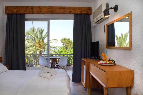 een hotelkamer met een bed en een bureau met een spiegel bij Hotel Hellas in Oud Epidauros