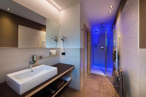 a bathroom with a white sink and a shower at Hotel Patrizia Dolomites Glamour in Moena
