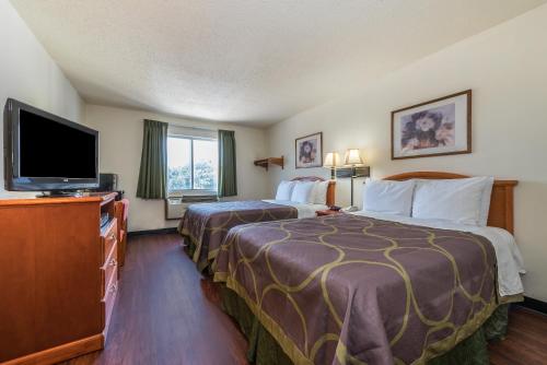 a hotel room with two beds and a flat screen tv at Super 8 by Wyndham Denton in Denton