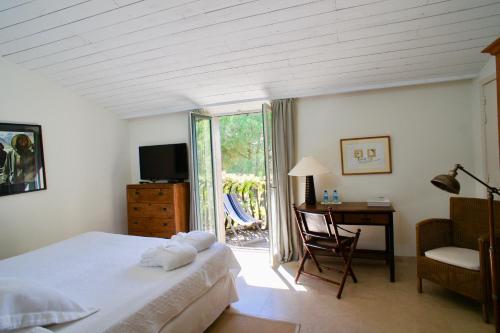 a bedroom with a bed and a desk and a window at Campagne les Jumeaux in Saint-Tropez