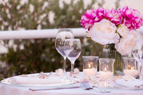 a table with wine glasses and a vase with pink flowers at Hotel Dei Pini in Alghero