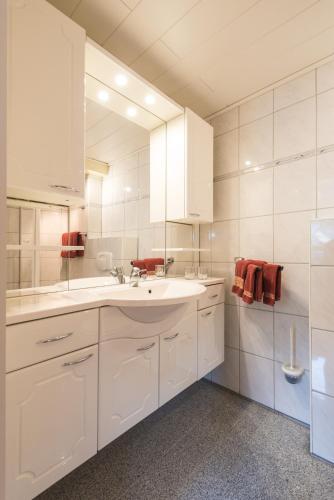 a white bathroom with a sink and a mirror at Moselromantik-Hotel zum Löwen in Ediger-Eller
