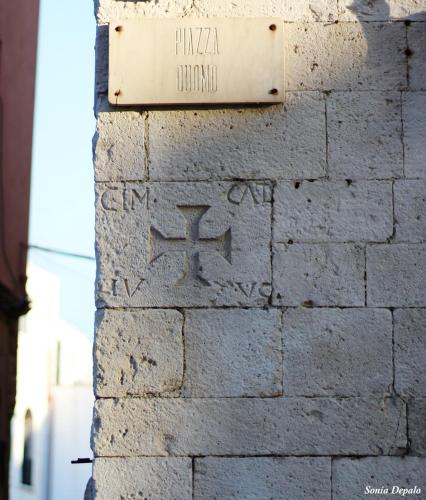 a sign on the side of a brick wall with graffiti at Palazzo Framarino dei Malatesta - Noble Floor - XIV Century in Giovinazzo