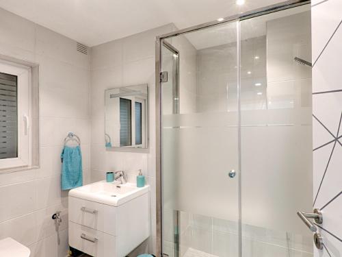 a white bathroom with a shower and a sink at Designer Finished Maisonette with Pool in Mellieħa