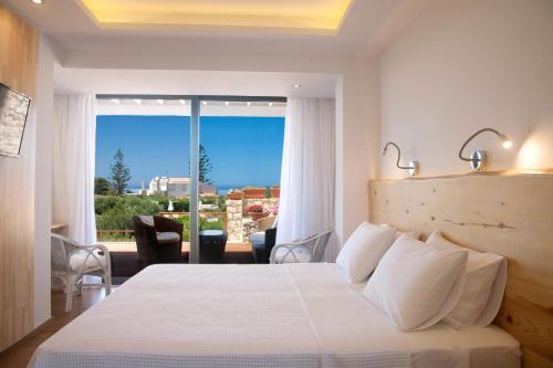 a hotel room with a bed and a large window at Artemis Village Apartments & Studios in Stavros