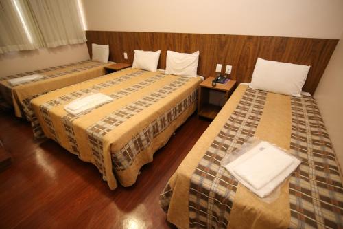 a hotel room with two beds in a room at Hotel Presidente Ipatinga in Ipatinga
