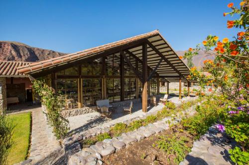a house with a wooden roof and a garden at Tierra Viva Valle Sagrado Hotel in Urubamba