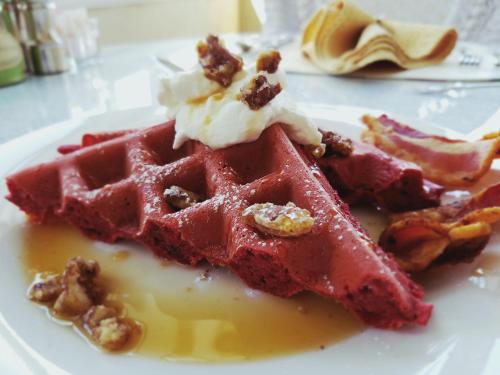 a white plate with a waffle with syrup and bacon at Albemarle Inn - Asheville in Asheville