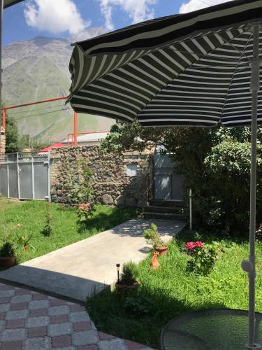 a patio with an umbrella in a yard at Soso Burduli's Guesthouse in Stepantsminda