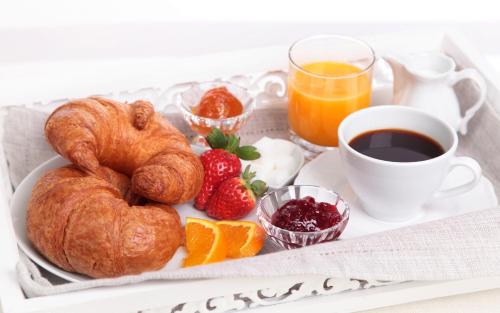 a breakfast tray with croissants and fruit and a cup of coffee at Serik & Geora Guesthouse in Sevan