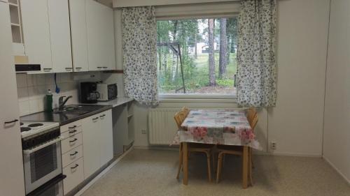 a small kitchen with a table and a window at Saimaa Hirsilinna Anttola in Anttola