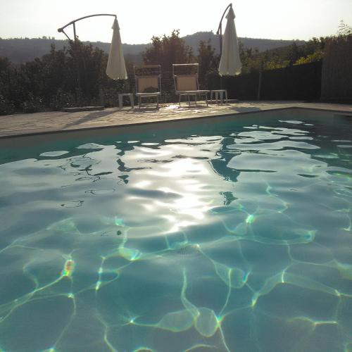 a swimming pool with two chairs and umbrellas at Casa Molly in La Morra