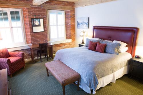 a bedroom with a bed and a chair and windows at The Common Man Inn & Restaurant in Claremont
