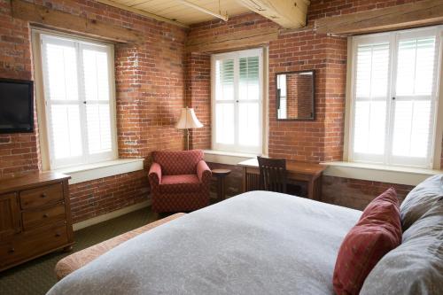 a bedroom with a brick wall and a bed and a chair at The Common Man Inn & Restaurant in Claremont
