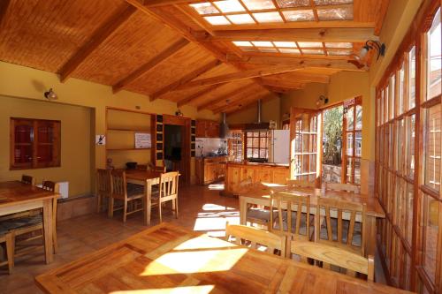 comedor grande con mesas y ventanas de madera en Hostal Corvatsch, en San Pedro de Atacama