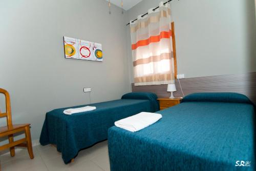 a hotel room with two beds and a chair at Camping las Catalinas in Ríolobos
